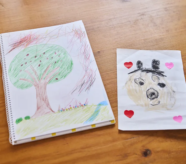 お家には子どもたち作のアートがたくさん。右は長女さんが書いて父の日にくれたというパパの似顔絵。左はご主人と長男くんの合作。